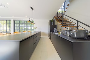 Una cocina moderna con una isla central, electrodomésticos integrados y una escalera con escalones de madera.