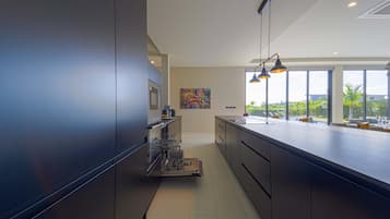 A modern kitchen with a large island, stainless steel appliances, and a view of the outdoors.