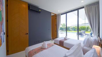 A hotel room with two beds, a large window with curtains, an air conditioning unit, and a view of a swimming pool and greenery outside.