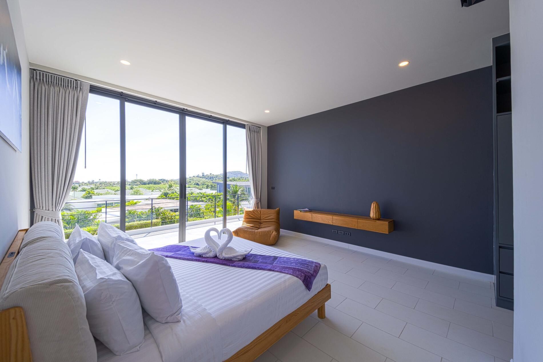Ein modernes Schlafzimmer mit einem großen Bett, Blick auf die Stadt und einer dunklen Wand.