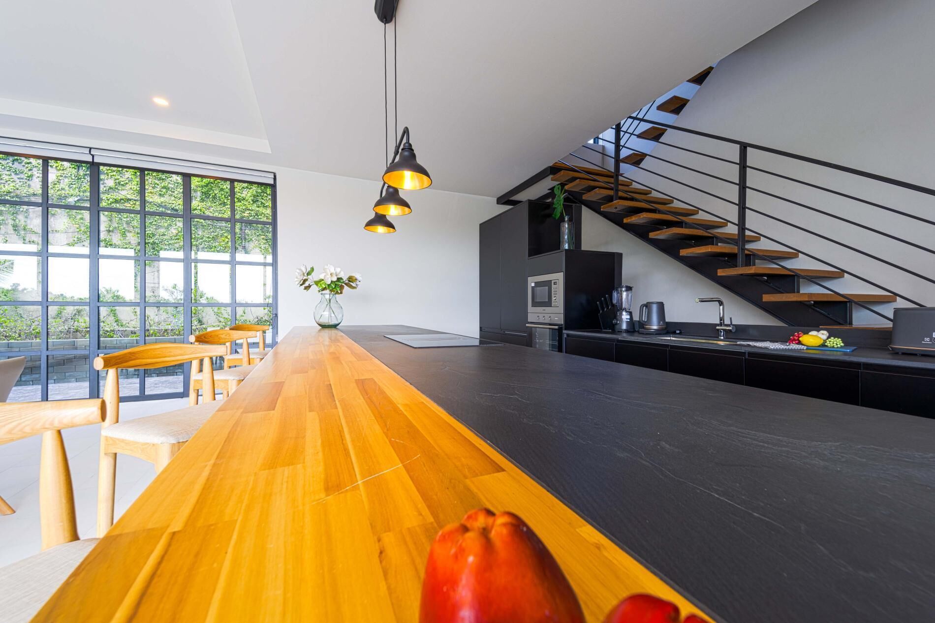 A modern kitchen with a wooden countertop, a built-in oven, and a black backsplash.