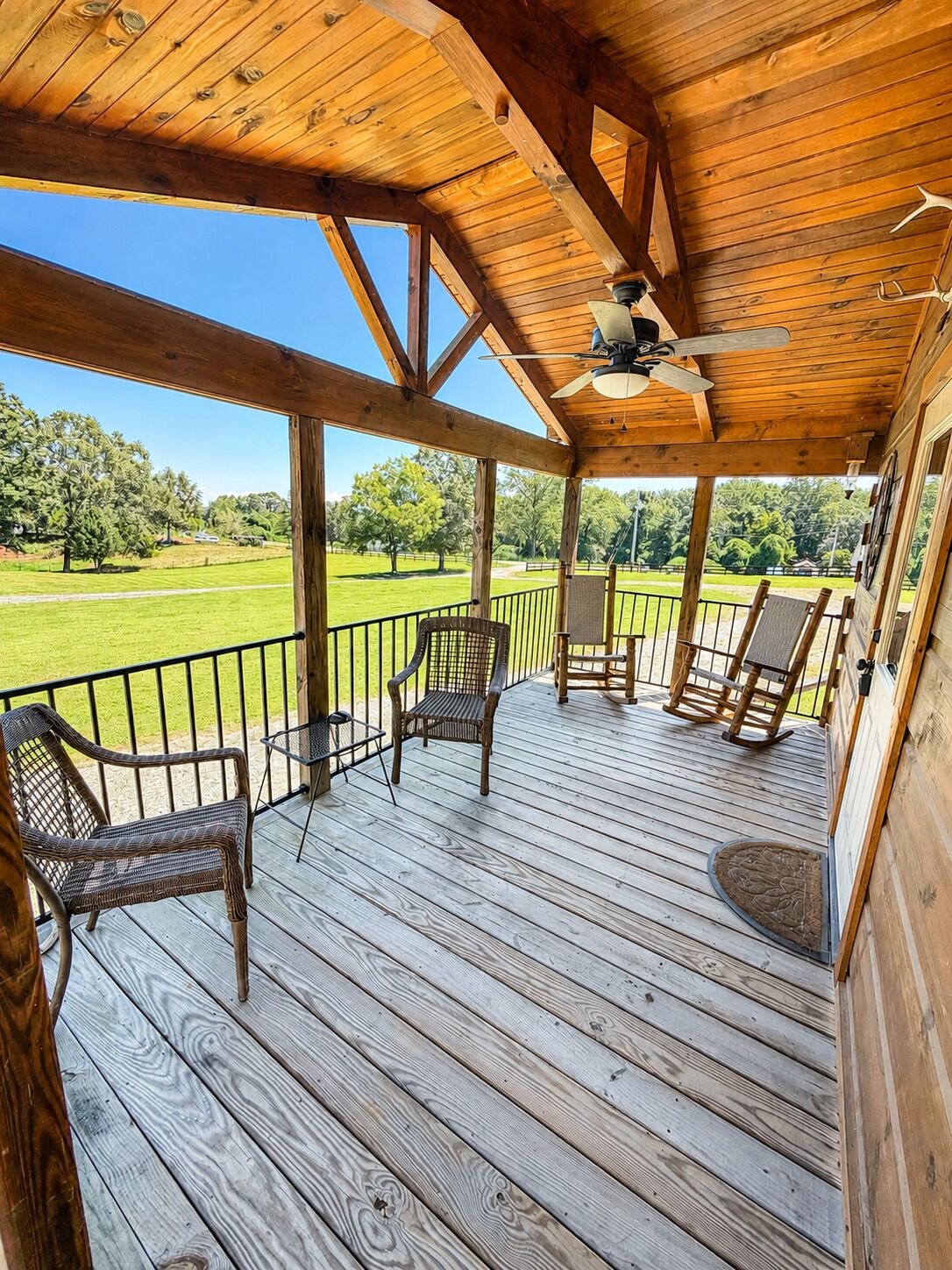 A wooden deck with outdoor seating and a ceiling fan.