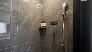 Een moderne badkamer met een bordje voor een natte vloer, een handdroger en een douchekop.