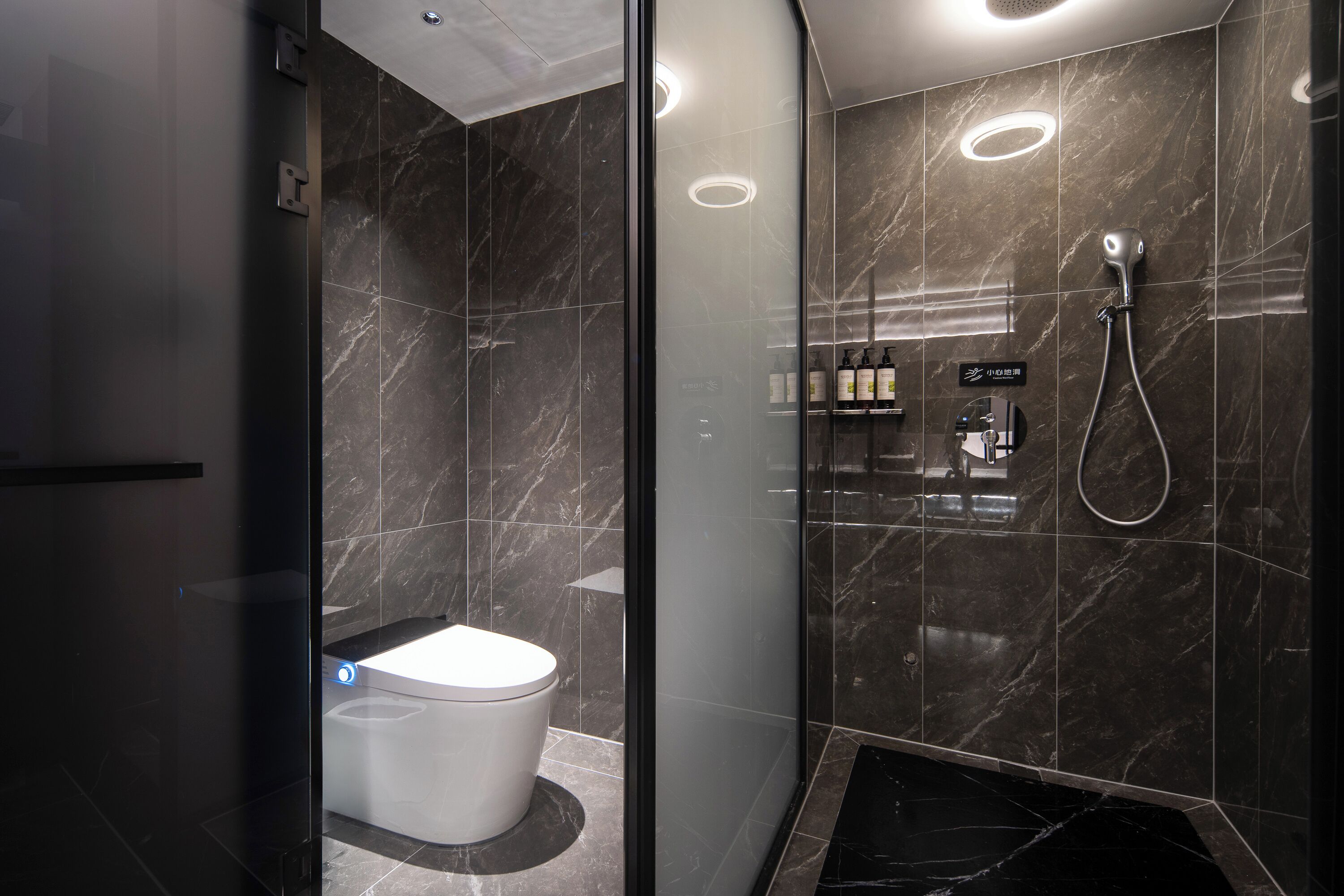 Un baño moderno con inodoro, ducha y tocador con artículos de aseo.