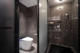 Un baño moderno con inodoro, ducha y tocador con artículos de aseo.