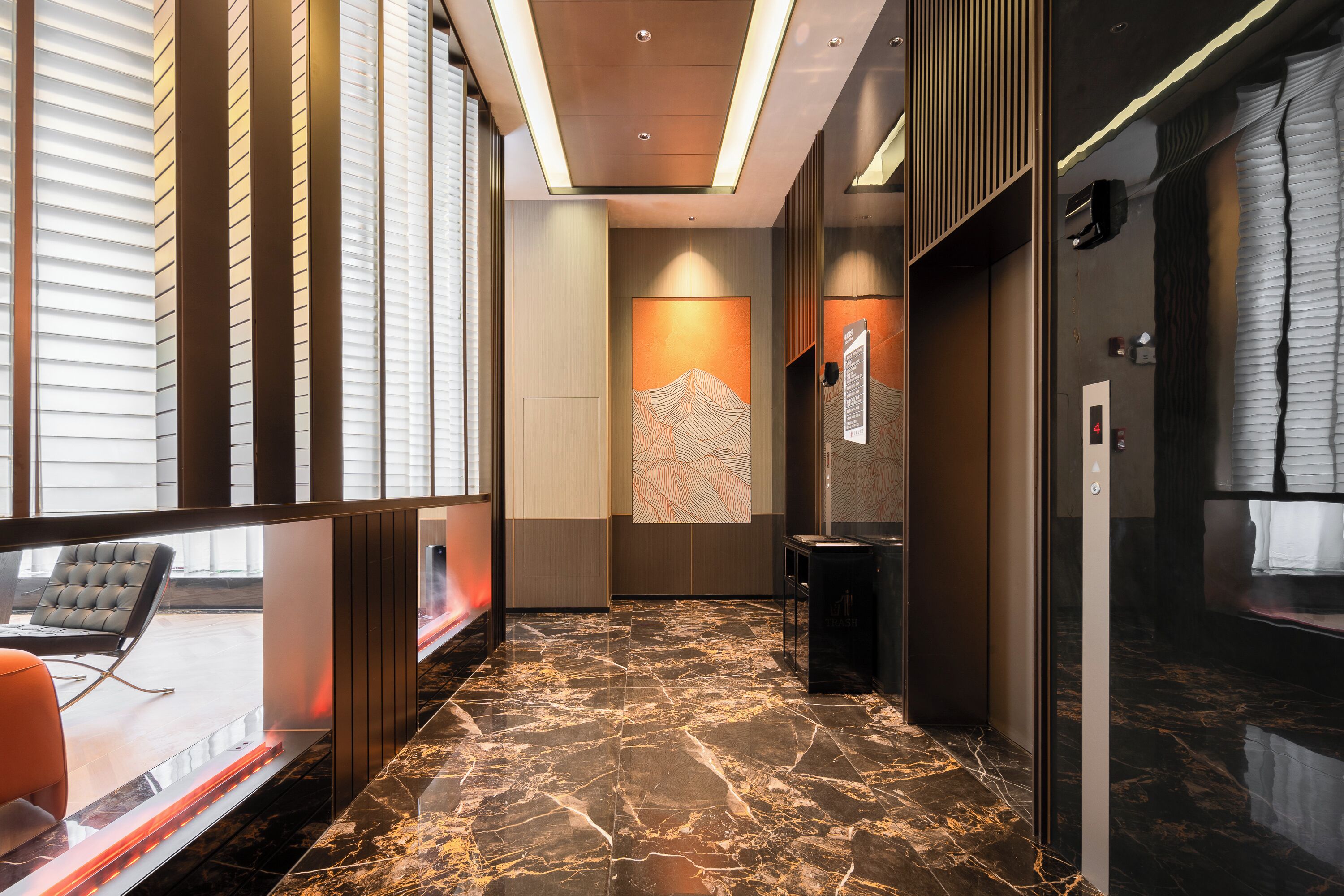 Un hall d’hôtel moderne avec un sol en marbre, un coin salon avec un canapé et une œuvre d’art accrochée au mur.