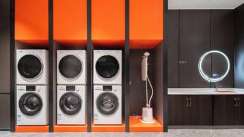 A laundry area with multiple washing machines and a sink with a mirror.
