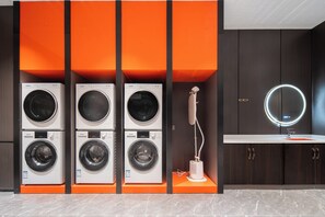 A laundry area with multiple washing machines and a sink with a mirror. - Licheng Donggu Hotel (Cangzhou)