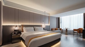 Habitación de hotel moderna con una cama grande, mesitas de noche, una zona de estar y vistas al exterior.