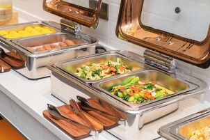 Un bufé con diversas opciones de comida, como verduras y platos de carne.