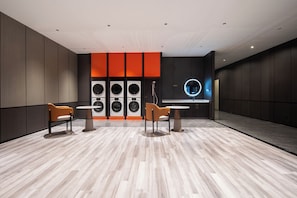 A modern laundry facility with multiple washing machines, two seating areas, and a circular mirror on the wall.