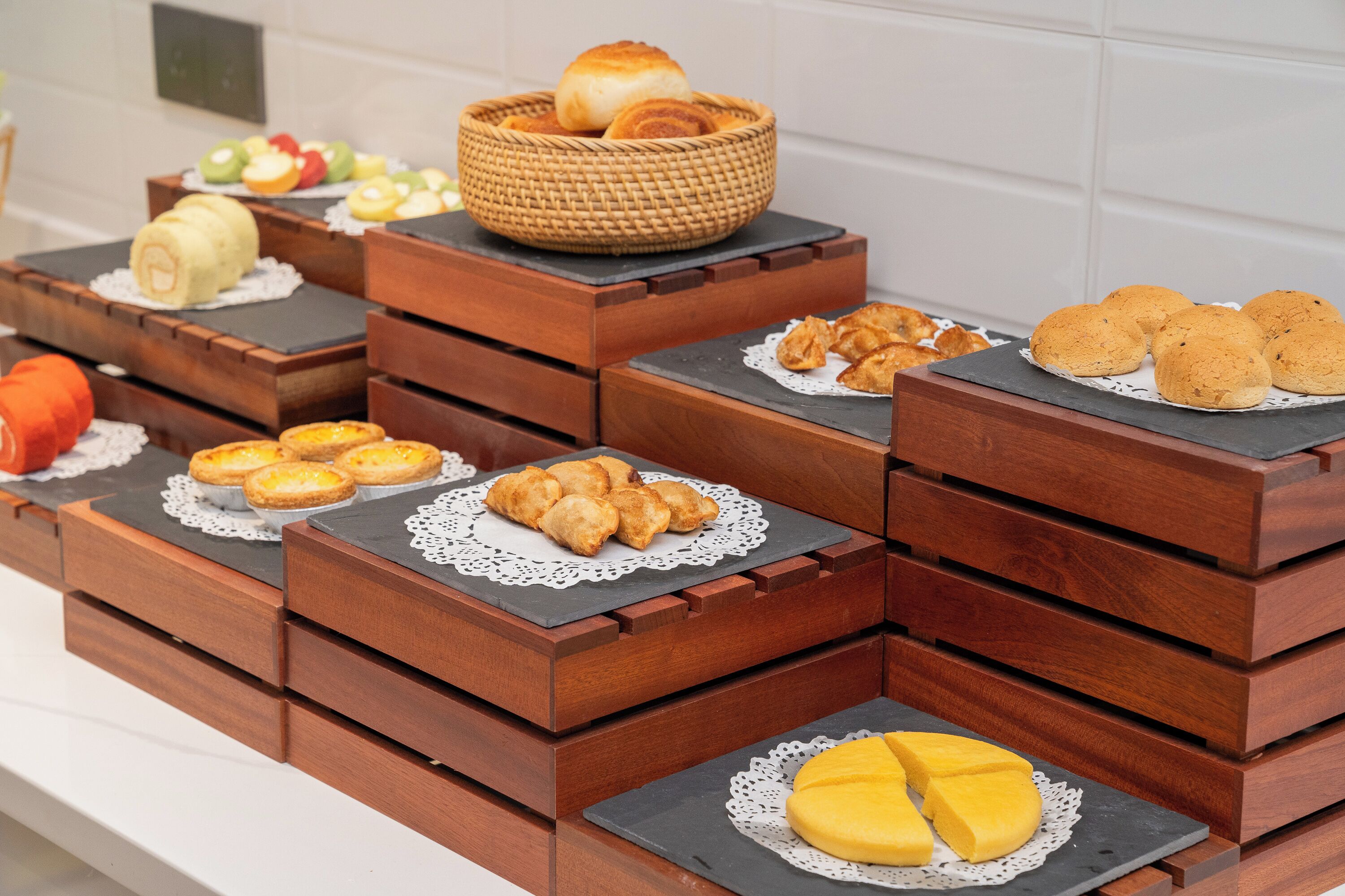 A buffet table with various baked goods, including bread rolls, pastries, and a pie.