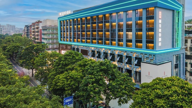 Un hôtel moderne, avec une façade en verre remarquable et des éléments d’éclairage néon.