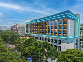 Un moderno edificio de hotel con una fachada de vidrio destacada y detalles de iluminación de neón.