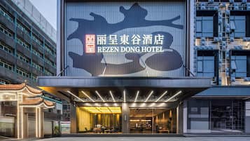 Un hotel con un gran cartel iluminado, una entrada moderna y un elemento arquitectónico tradicional.