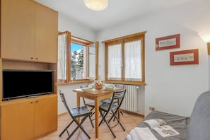 A compact living space with a dining area, a television, and a sofa. - Casa Regia (Sestriere)