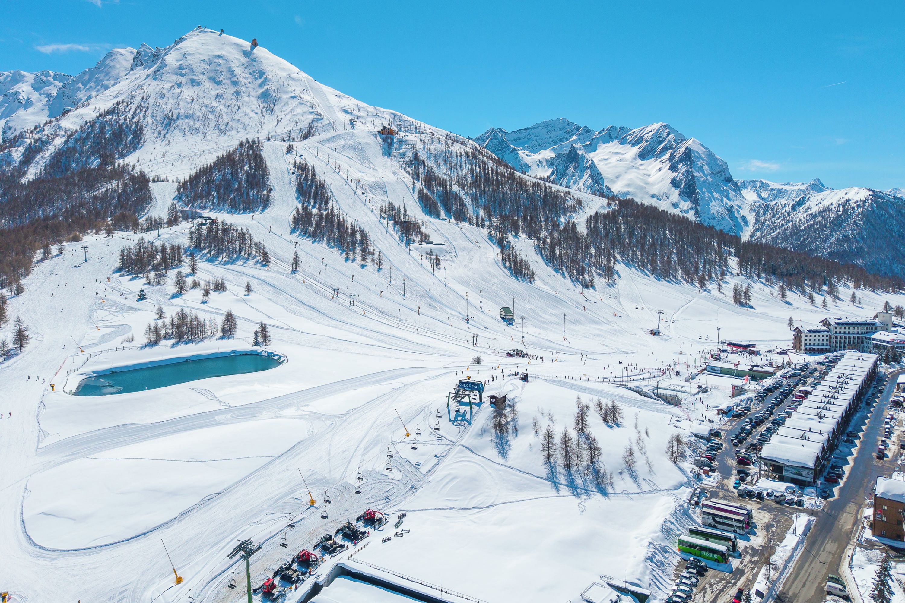 A snow-covered mountain with ski slopes and a parking lot.
