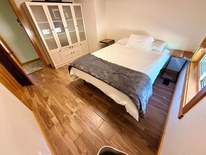 A bedroom with a bed, a wardrobe, and a wooden floor.