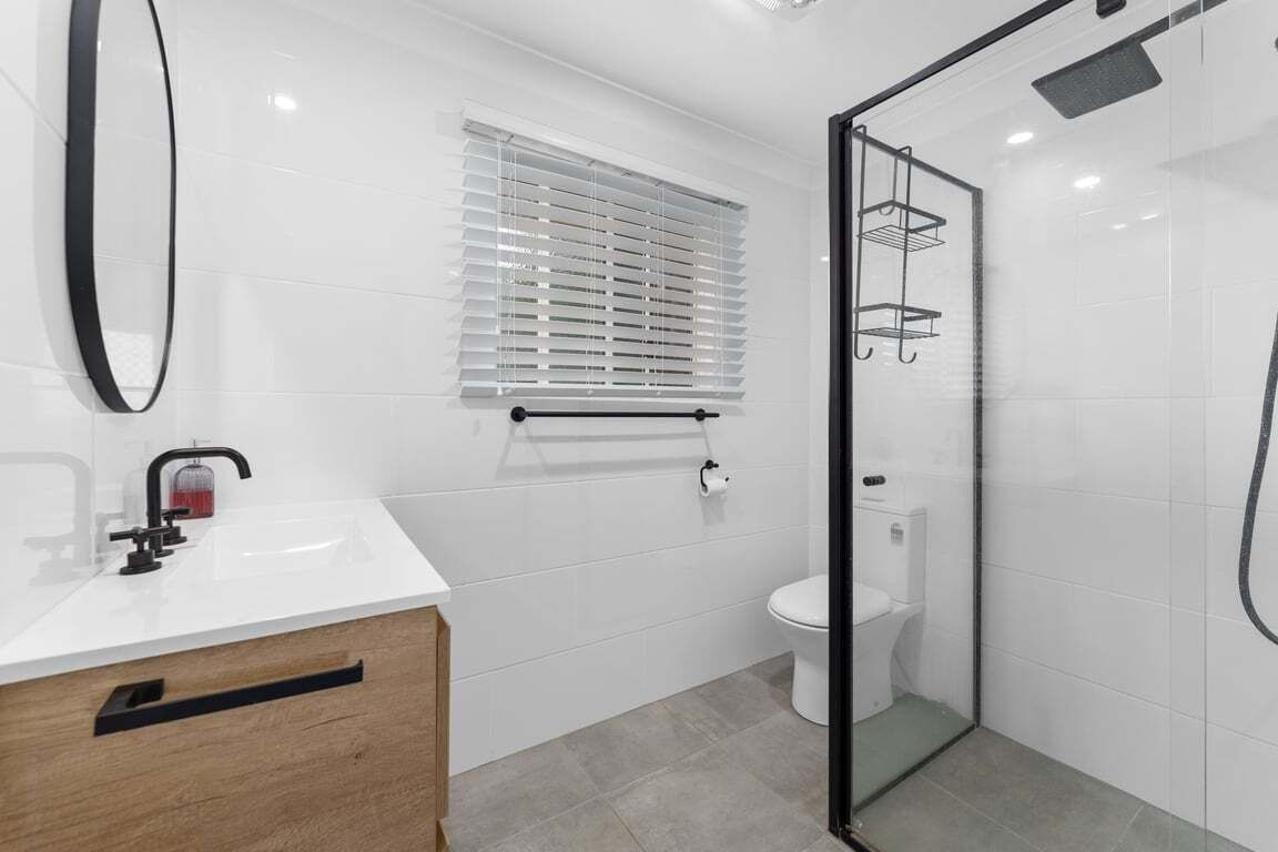 A modern bathroom with a glass shower enclosure, a white sink, and a toilet.