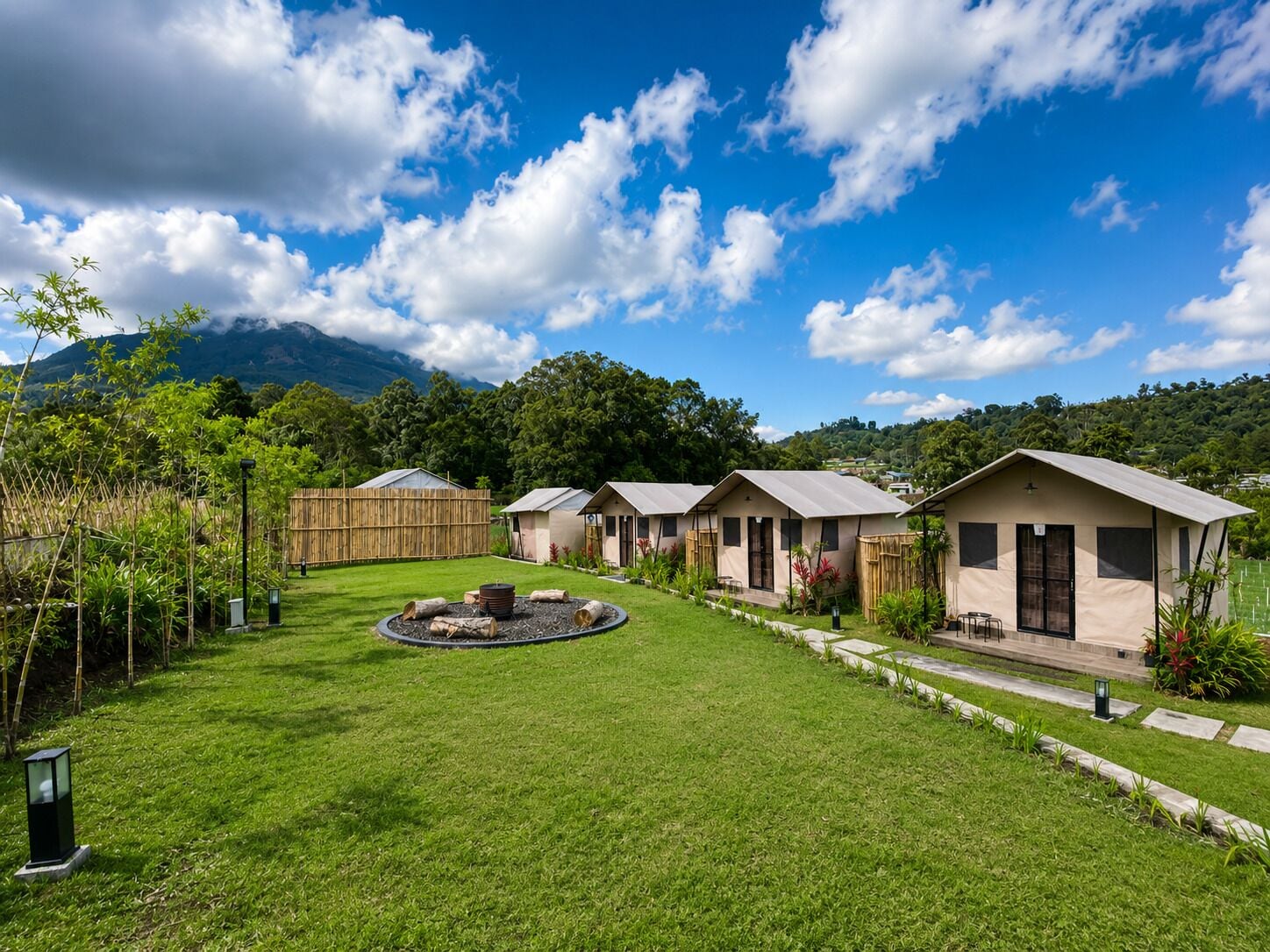 A row of single-story cabins with a well-maintained lawn and a circular fire pit in the center.