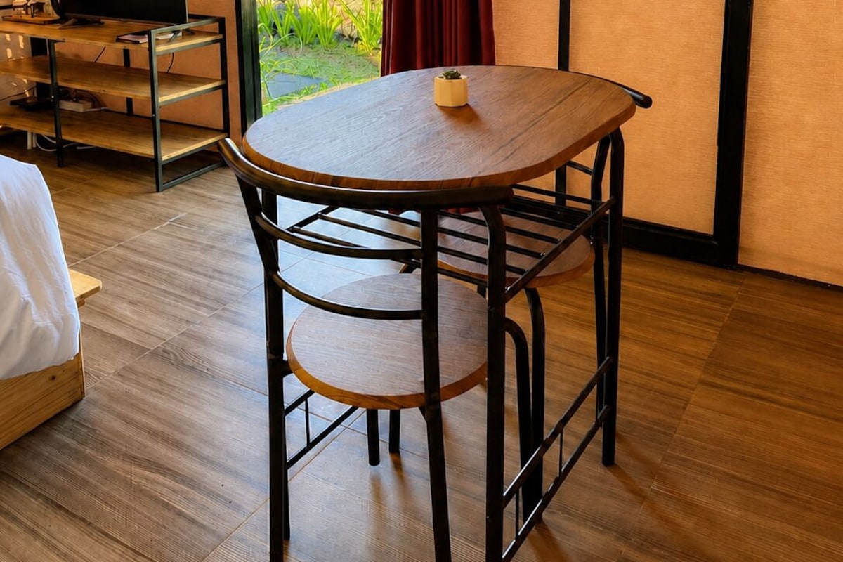 Una habitación con cama, una mesa con silla, televisión y vistas al exterior.