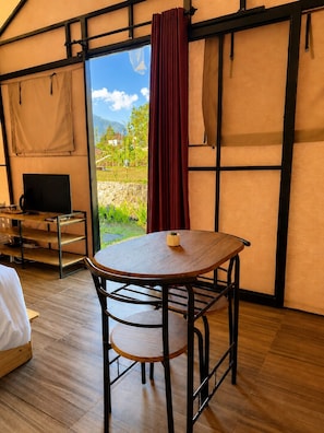 Una habitación con cama, una mesa con silla, televisión y vistas al exterior.