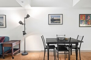 A dining area with a table and chairs, a floor lamp, and framed pictures on the wall. - Melbourne 1-Bed Apartment Flinders Street (Melbourne)