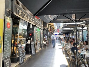 An outdoor café with tables and chairs, a sign for 'DEGRAVES', and a menu board. - Melbourne 1-Bed Apartment Flinders Street (Melbourne)