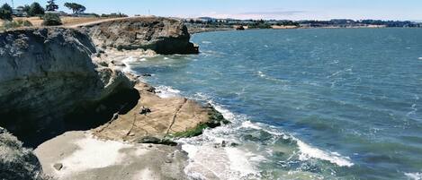 A coastal landscape with a rocky shoreline and clear blue water.