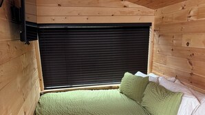A single bed with a green quilt, a wooden headboard, and a black headboard.