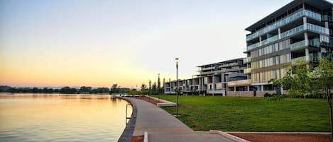 A modern building with multiple balconies overlooking a calm body of water.