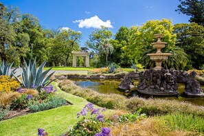 Ein Garten mit einem Brunnen, einem Gartenhäuschen und verschiedenen Pflanzen.