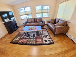 A living room with a brown leather sofa, a coffee table, and a television on a stand. - Awesome 3-bedroom apartment in Anchorage perfect for your getaway (Anchorage)
