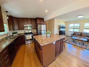 Una cocina moderna con encimeras de granito, electrodomésticos de acero inoxidable y armarios de madera.
