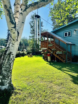 A house with a wooden deck, a metal tower, and a grassy yard. - Awesome 3-bedroom apartment in Anchorage perfect for your getaway (Anchorage)