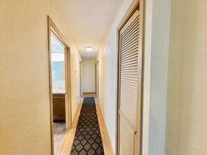 A narrow hallway with a patterned carpet, wooden flooring, and a door with blinds. - Awesome 3-bedroom apartment in Anchorage perfect for your getaway (Anchorage)