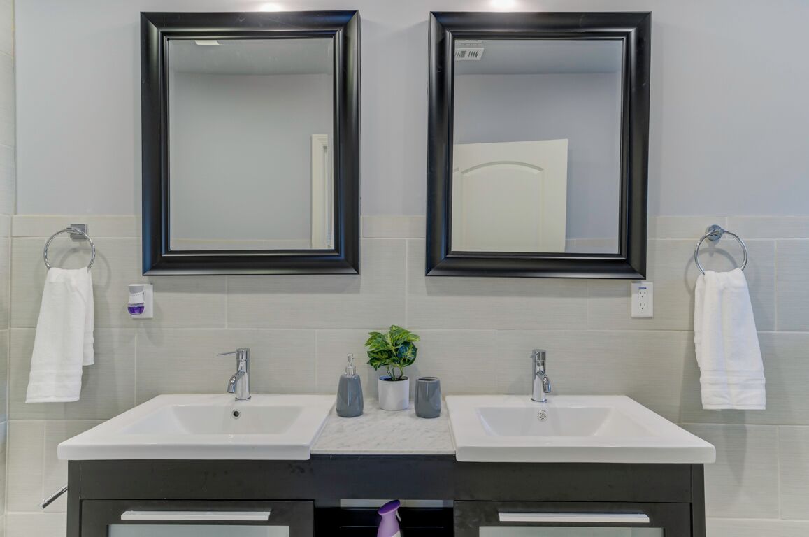 Een badkamer met twee wastafels, twee spiegels en een potplant.