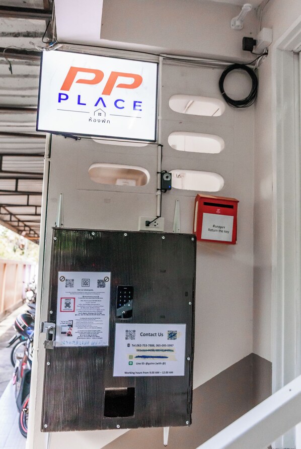 Un clavier de sécurité, une boîte rouge pour déposer les clés et une enseigne indiquant « PP PLACE » sur la façade d’un immeuble.