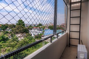 A balcony with a chain-link fence overlooking a residential area and a swimming pool. - KID-DE HOUSE Bangsaen (Mueang Chon Buri District)
