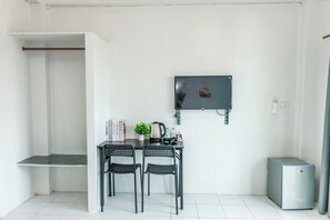 Une petite cuisine équipée avec une table, des chaises, un téléviseur et un réfrigérateur.