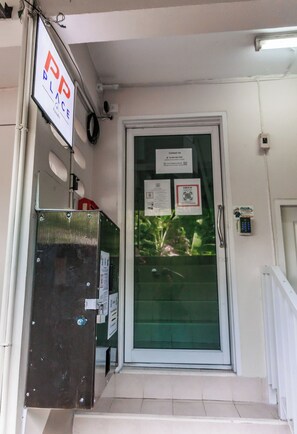 L’entrée d’un hôtel, avec une porte en verre, un clavier de sécurité et un panneau indiquant un espace de stationnement.