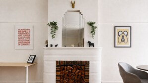 A modern living room with a fireplace, a dining area with a table and chairs, and decorative wall art. - Sophisticated East Melbourne Retreat by Ready Set Stay (East Melbourne)