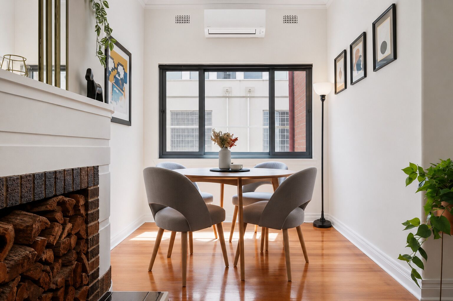 A dining area with a table, chairs, a vase with flowers, and a window with a view of buildings.