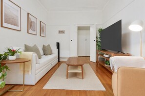 A modern living room with a sofa, coffee table, TV, and a flat-screen TV on a stand. - Sophisticated East Melbourne Retreat by Ready Set Stay (East Melbourne)