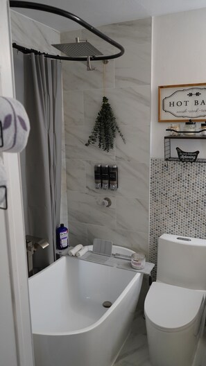 Un baño moderno con una bañera independiente, ducha y retrete.