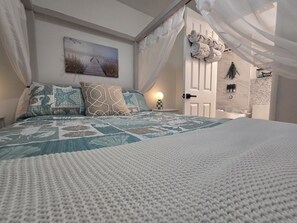 A bedroom with a large bed, a painting on the wall, and a door leading to another room.