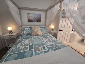 Une chambre à coucher comprenant un lit, deux tables de chevet, une commode, une fenêtre avec des rideaux et une porte.