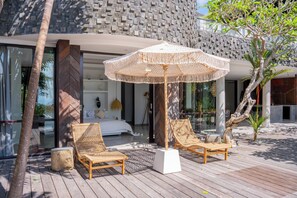 A modern outdoor seating area with two wicker chairs and a large woven umbrella. - Villa Moso (Kabupaten Badung)