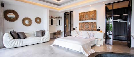 A modern bedroom with a bed, a white sofa, and a ceiling fan.
