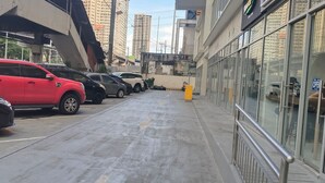 Uma área de estacionamento com vários carros, um hidrante amarelo e um edifício com grandes janelas.